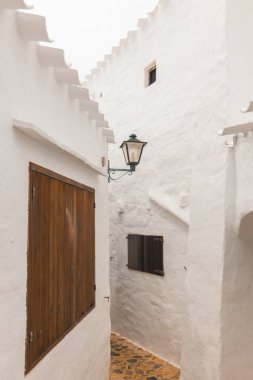 Menorca 'daki Binibeca kasabası. Dar sokaklar ve ahşap elementli beyaz duvarlar, İspanya 'da Akdeniz mimarisi
