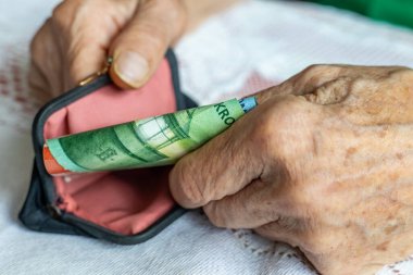Norveç parası. Elinde bir tomar banknotla çanta tutan yaşlı bir kadının elleri. konsept, kıdemli finans, Norveç 'te emeklilik sistemi