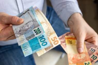 Brezilya parası. İş adamı Brezilya reais 'iyle elini uzatıyor. BRL banknotları. Finansal iş kavramı
