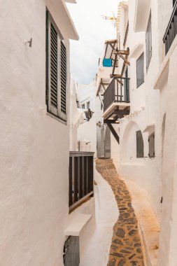 Narrow streets of the beautiful village of Binibeca on Menorca. White plastered house walls with wooden elements. A charming town in Spain on the Balearic Islands clipart