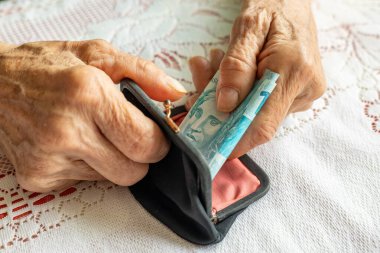 Brezilya parası. Kıdemli bir kadının elleri bir tomar banknot tutuyor. Finansal konsept. Brezilya 'nın mali durumu