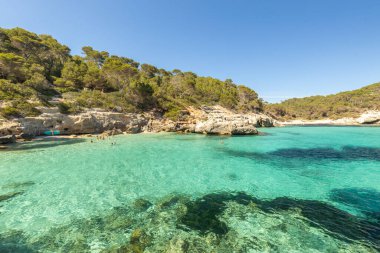 Menorca adasının ve Cala Mitjana plajının çok güzel kıyıları. Gök mavisi su, Akdeniz 'in berrak suyu. İspanya 'nın tatil manzarası