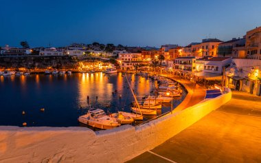 Gün batımından sonra El Castell Menorca. Eski liman manzarası ve barlarla dolu rıhtım manzarası, şehir manzarası. Seyahat konsepti. İspanya turistik merkezleri