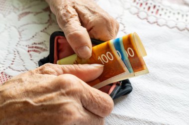 Yaşlı bir kadın cüzdanından İsrail şekeri çıkarıyor. Finansal konsept. İsrail 'deki yaşlıların ekonomik durumu