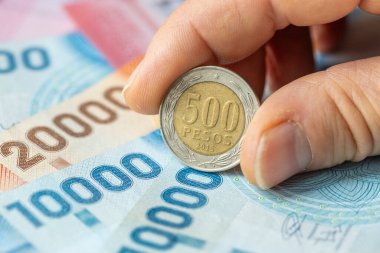 Şili parası. Parmakların içinde 500 peso var. Masada duran banknotlar. İş konsepti. Tasarruf artırılıyor, kapat