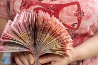 Endonezya işi ve finans. Finansal başarı kavramı. Elinde bir yığın Endonezya parası tutan bir kadın.