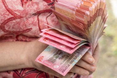 Endonezya parası. Finansal başarı kavramı. Endonezya Rupisi 'nden koca bir deste tutan kadın. Yüz bin banknot.,