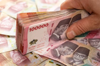 Endonezya parası. Finansal başarı kavramı. Büyük bir Endonezya rupiası destesiyle el ele tutuşmak. 100 bin banknot, kapatın.