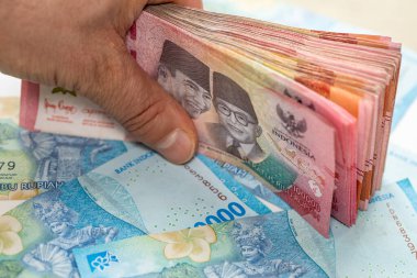Endonezya parası. Finansal başarı kavramı. Büyük bir Endonezya rupiası destesiyle el ele tutuşmak. 50 ve 100 bin banknot, kapatın.