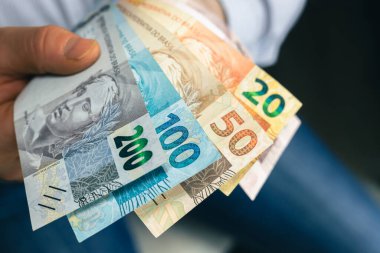Brezilya parası. İş adamı Brezilya reais 'iyle elini uzatıyor. BRL banknotları. Finansal iş kavramı