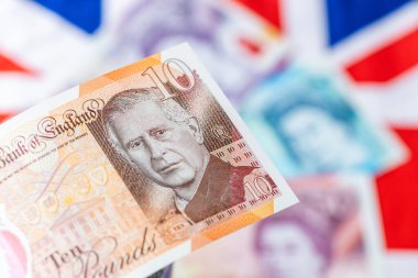 İngiltere Merkez Bankası tarafından Haziran 2024 'te çıkarılan King Charles III ile Yeni Britanya Para Birimi. Arka planda, Bayrak ve Kraliçe 'nin resmine sahip eski banknotlar