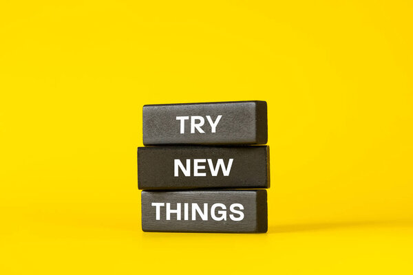 Try new things. Slogan on wooden blocks. Business concept. Self-fulfillment and development. Beautiful yellow background