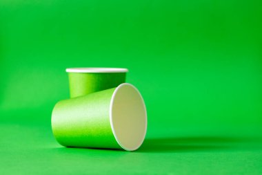 Yeşil arka planda yeşil kağıt bardaklar. Boşluğu kopyala