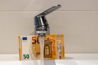 AB ülkelerinde suyun maliyeti. 50 Euro 'luk banknot ve akan musluk suyu. Finansal ekonomik konsept, ev bütçesi, kamu hizmetleri ve ücretler. Kapat.
