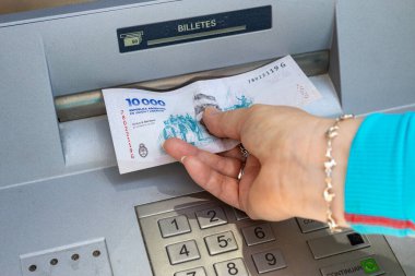Arjantin parası. Bir kadın ATM 'den 10.000 pezoluk Arjantin banknotunu çekiyor. Mali konsept