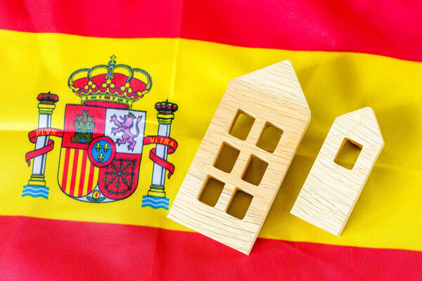 Испанская недвижимость. Деревянные миниатюры домов на фоне испанского флага. Экономическая концепция бизнеса. Повышение цен на жилье. Рост расходов на аренду. Экономическая проблема Испании. close up