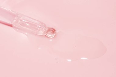 Sıvı damlayan kozmetik pipeti ve pembe arka plan, serum, serum, jel, vitamin, su, yağ damlaları