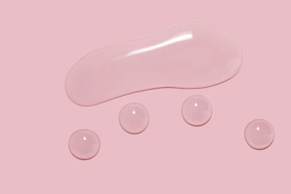 Büyük miktarda kozmetik serumu, sıvı, su, pembe arka planda jel.