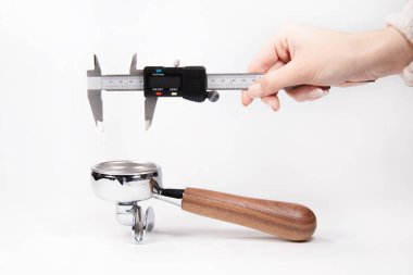 Elin dijital kalibreli paslanmaz çelik espresso iskeletiyle ahşap saplı beyaz arka planda ayarlanmış. Kahveci aletlerinde ve kahve hazırlamada hassasiyeti göstermek için mükemmel..