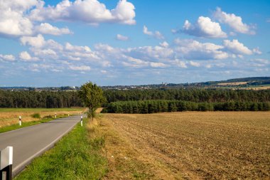 bir tarlanın panorma manzarası yol ve mavi gökyüzü, arka planda dağ.