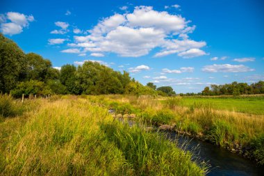 Yeşil çayır ve mavi gökyüzünün panoramik görüntüsü. Önünde bir nehir var. Yüksek kalite fotoğraf