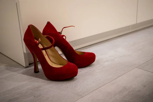 Red high heels on a White wood floor in front of a Closet to dress up.