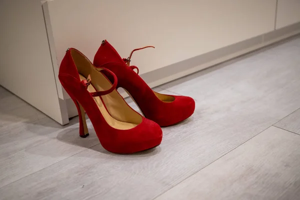 Red high heels on a White wood floor in front of a Closet to dress up.
