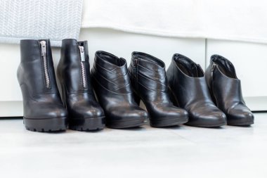 Beyaz bir dolabın önünde yüksek topuklu üç çift siyah bot. Yüksek kalite fotoğraf