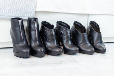 Beyaz bir dolabın önünde yüksek topuklu üç çift siyah bot. Yüksek kalite fotoğraf