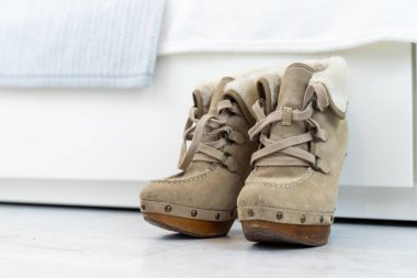 Beyaz bir gardırobun önünde yüksek topuklu bej kış çizmeleri. Yüksek kalite fotoğraf