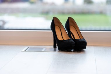 Kırmızı yüksek topuklu ayakkabılar pencerenin önünde ve ışıklı zeminde. Yüksek kalite fotoğraf