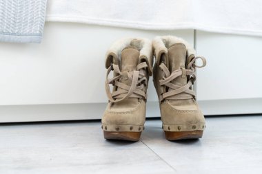 Beyaz bir gardırobun önünde yüksek topuklu bej kış çizmeleri. Yüksek kalite fotoğraf