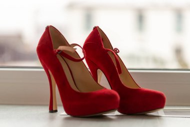 Kırmızı yüksek topuklu ayakkabılar pencerenin önünde ve ışıklı zeminde. Yüksek kalite fotoğraf