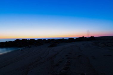 Sahilde mavi saat, suda kayalar, uzun pozlama. Yüksek kalite fotoğraf