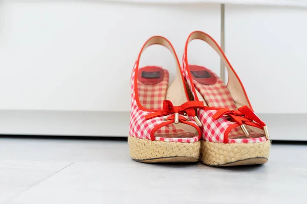Red White open shoes with a high wedge heel in front of a closet. High quality photo