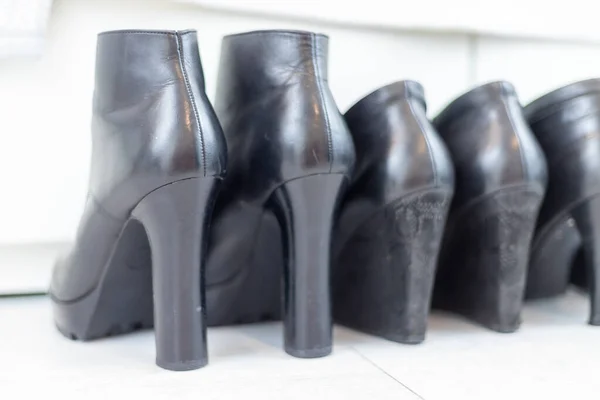 three pairs of black boots with high heels in front of a white closet. High quality photo