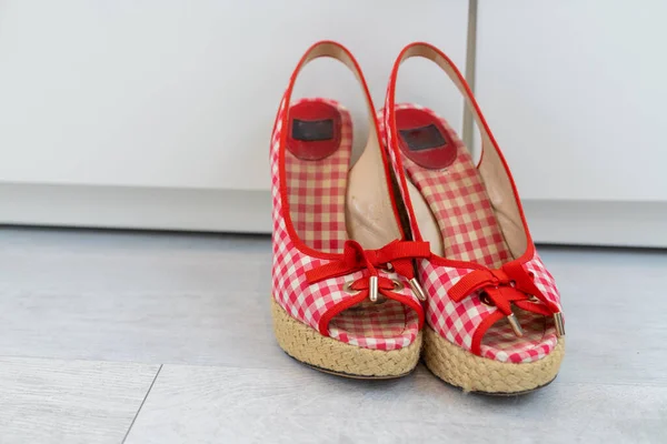 Red White open shoes with a high wedge heel in front of a closet. High quality photo