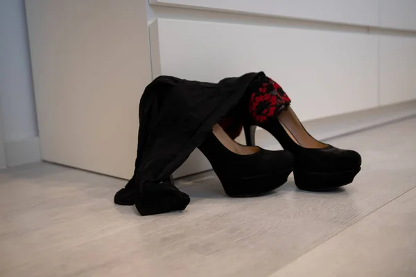 A pair of tall women\'s High Heels and stockings in front of a closet black pumps.