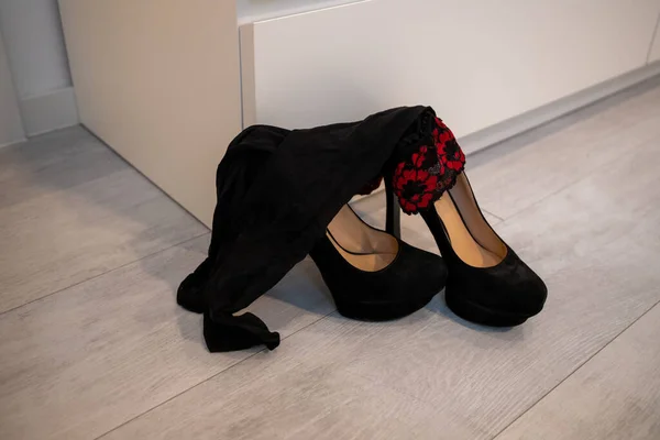 A pair of tall women's High Heels and stockings in front of a closet black pumps.