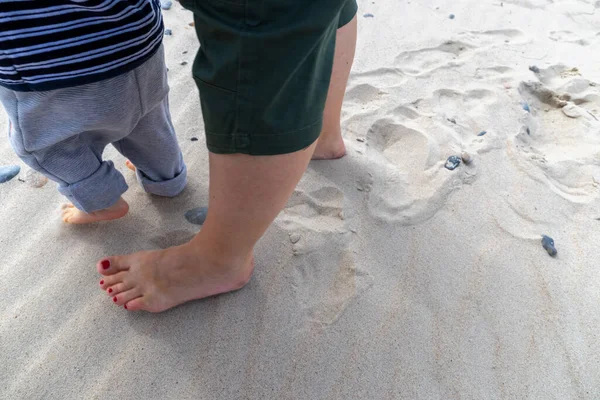 Women and baby feet walk on the beach in the sand. High quality photo