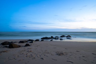 Deniz kenarında, kumdaki kayalarla uzun süre çekim, mavi saat. Yüksek kalite fotoğraf