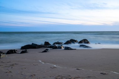 Deniz kenarında, kumdaki kayalarla uzun süre çekim, mavi saat. Yüksek kalite fotoğraf