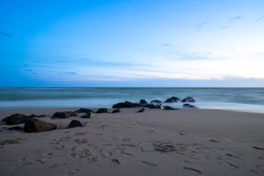 Deniz kenarında, kumdaki kayalarla uzun süre çekim, mavi saat. Yüksek kalite fotoğraf