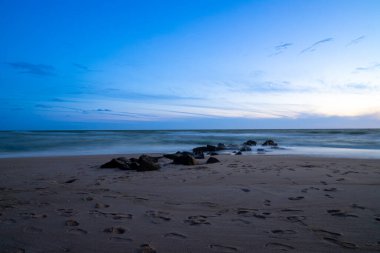 Deniz kenarında, kumdaki kayalarla uzun süre çekim, mavi saat. Yüksek kalite fotoğraf