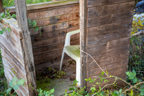 Старый охотничий киоск с белым пластиковым стулом. Высокое качество фото