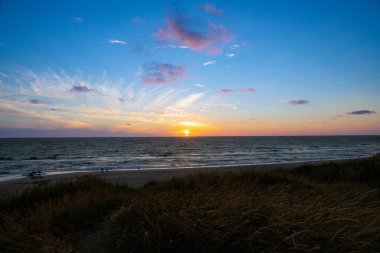 Kum tepeleri arasında Danimarka sahilinden Kuzey Denizi 'ne gün batımı. Yüksek kalite fotoğraf