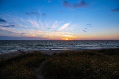 Kum tepeleri arasında Danimarka sahilinden Kuzey Denizi 'ne gün batımı. Yüksek kalite fotoğraf