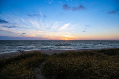 Kum tepeleri arasında Danimarka sahilinden Kuzey Denizi 'ne gün batımı. Yüksek kalite fotoğraf