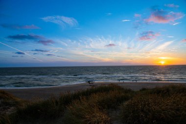 Kum tepeleri arasında Danimarka sahilinden Kuzey Denizi 'ne gün batımı. Yüksek kalite fotoğraf
