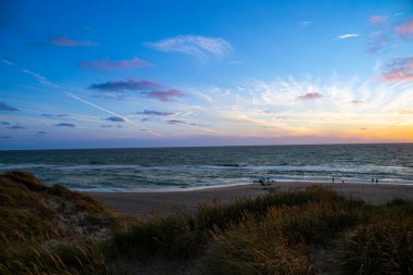 Kum tepeleri arasında Danimarka sahilinden Kuzey Denizi 'ne gün batımı. Yüksek kalite fotoğraf